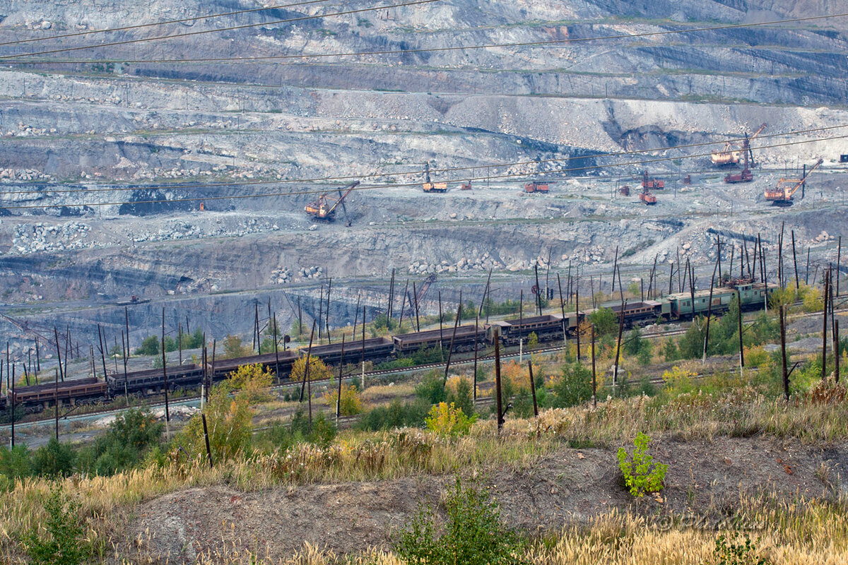 Поэтому сразу же начинаем спуск вниз по старым деревянным лестницам. Постепенно открываются новые горизонты.
Сначала выборка грунта и добытого угля велась автотранспортом. Но с увеличением объемов добычи автотранспорт уже не справлялся и в разрезе была проложена железнодорожная ветка которая идет по спирали снизу вверх.

