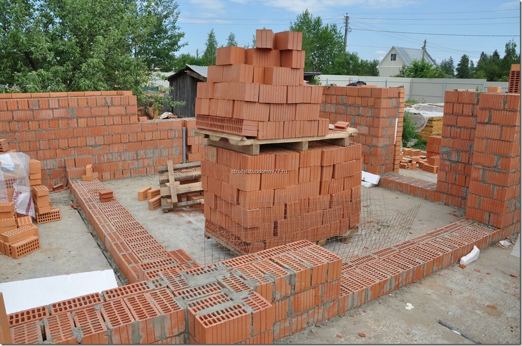На фото: процесс строительства дома из кирпича