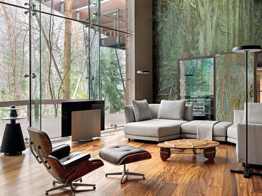 Сложная форма загородного дома была определена желанием хозяина сохранить деревья на участке. Объёмы здания спроектированы так, чтобы наилучшим образом вписаться в окружающий ландшафт. Одна из стен двусветной гостиной выполнена полностью из стекла, она обращена во внутренний двор и имеет дополнительный выход. Кресло Lounge Chair and Ottoman, Eames. Кофейный столик Rock’n’roll, Team 7.