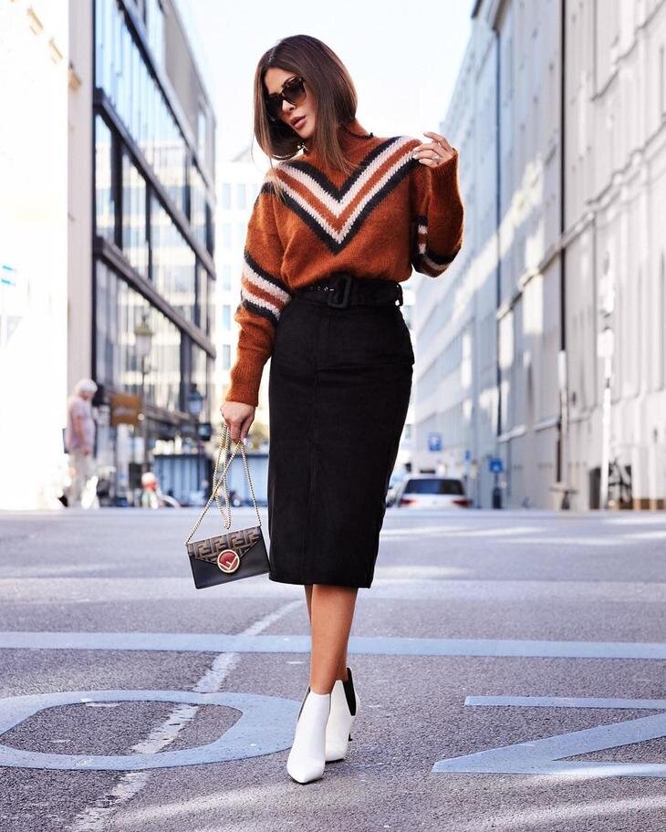 Узкая юбка и широкий свитер гармонично дополняют друг друга. Белая обувь и актуальный принт освежают образ