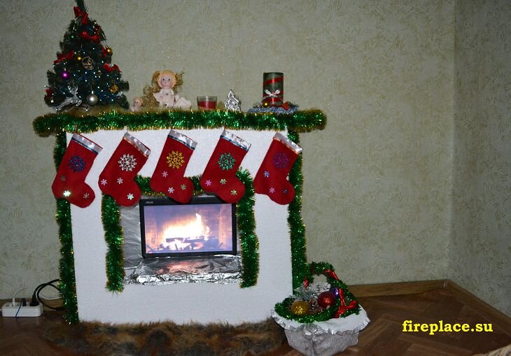 Если у вас нет дома камина, то его можно сделать самостоятельно из подручных материалов. Сам портал делается из коробок, а топку можно либо нарисовать, либо распечатать. 