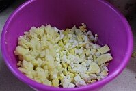 Прежде всего следует отварить до мягкости все необходимые продукты: корнеплоды и яйца. Остудить ингредиенты при комнатной температуре, промыть и очистить от скорлупы и кожицы. Нужно измельчить вареный картофель и яйца мелким кубиком. Всыпать рубленые продукты в большую ёмкость для смешивания салатов.