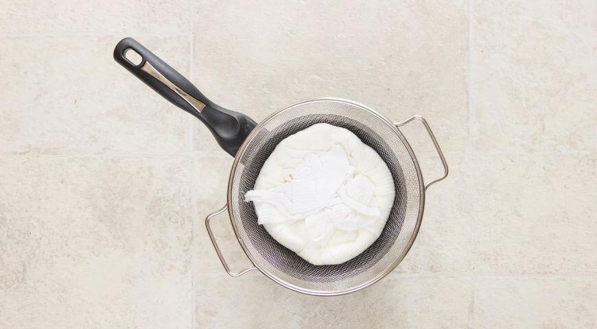 Приготовьте тесто для классических сырников. Творог выложите в тонкое полотенце и поместите в дуршлаг под груз на пару часов. Это обязательно – лишняя жидкость заставит вас добавлять в творог муку.