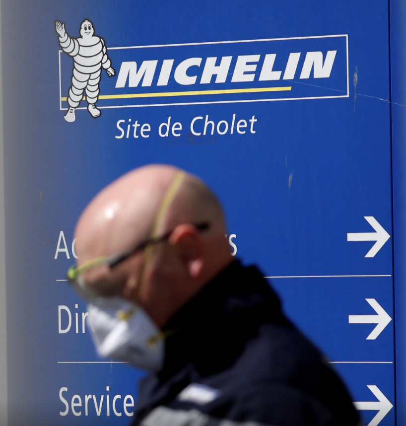  сотрудник в защитной маске проходит мимо входа на завод шин Michelin в Шоле, Франция, 14 апреля 2020 года. 