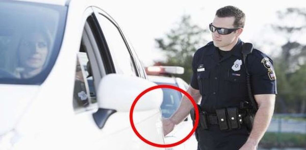 Полицейский прикасается к задней части автомобиля и оставляет свой отпечаток пальца.