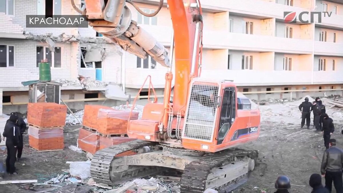 Снос ЖК Кадетский в Краснодаре. Дом,  c уже проданными квартирами, снесли, потому что он был якобы неправильно построен. Хозяев квартир вывели на улицу при помощи полиции и держали, пока экскаватор ломал их новые квартиры. Застройщик сбежал с деньгами.