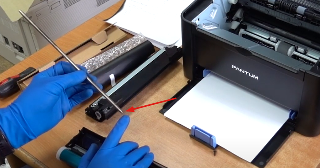 Обрезанным концом полностью заводим ось с левой стороны в фотобарабан