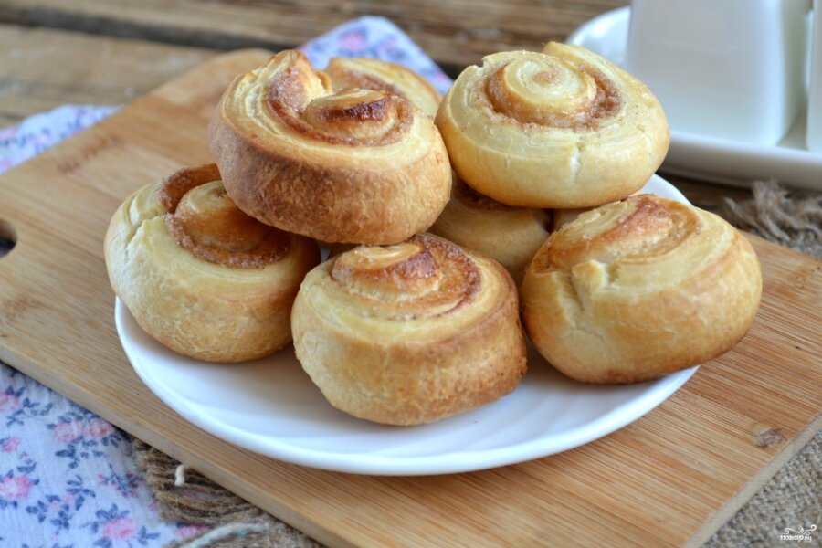 Быстрые булочки с корицей из слоеного теста. Эти булочки можно приготовить за полчаса! Пока духовка нагревается, вы уже посыпаете готовое тесто корицей с сахаром и вырезаете заготовки. А запекать надо всего 15 минут. Ингредиенты: 400 г готового слоеного теста (дрожжевого или бездрожжевого); 50 г сахара; 15 г корицы; яйцо для смазывания. Тесто заранее разморозьте на присыпанном мукой столе. Затем пласт теста посыпьте смесью сахара и корицы. Сверните рулет и нарежьте толстыми кусочками. Идея! Готовые булочки можно полить глазурью из взбитого с сахарной пудрой творожного сыра (типа маскарпоне). Вкуснятина! Выкладывайте заготовки на противень, застеленный пергаментом, и смазывайте взбитым яйцом при помощи кондитерской кисточки. Запекайте 15 минут при температуре 190-200 градусов. 
