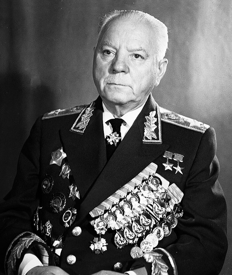Климент Ефремович родом с города Лисичанск, ныне Луганской области Украины. С самого начала Великой Отечественной войны вступил в  Государственный комитета обороны. Уже 10 июля возглавил войска Северо-Западного направления, а затем и стал командующим Ленинградским фронтом. В 1942-1944 годах координировал действия советских войск, выполнявшим задачи по прорыву блокады Ленинграда. В это же время проводил подобную работу по освобождению полуострова Крым. Более того в начале сентября 1942 года получил должность Главнокомандующего партизанским движением. При нём значительно улучшилось управление соединениями, были решены ряд проблем по обеспечению частей всем необходимым, серьёзно возросла эффективность их действии. Партизанские отряды по всем показателям начали напоминать строевые части действующей армии. В начале апреля 1943 года назначен руководителем Трофейного комитета. Провёл её реорганизацию, в результате чего и её эффективность по сбору военной техники, вооружений, металлолома и прочих ценностей значительно возросла. Участник Тегеранской конференции. Разработал документ по завершению боевых действий, основу которого составляла безоговорочная капитуляция Рейха. Дважды Герой Советского Союза, Герой Социалистического Труда, Кавалер 14 орденов. Умер в 1969 году. (Фото взято из открытых источников).