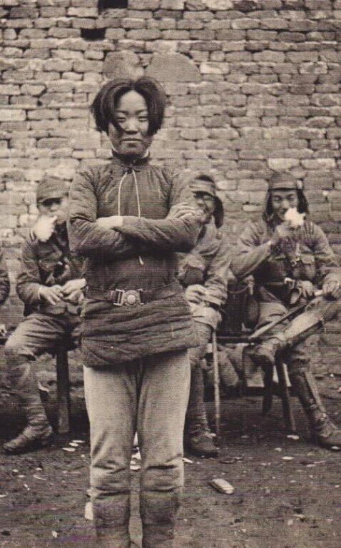 Молодая китайская девчонка презрительно улыбается, глядя в объектив неизвестного японского фотографа. За ее спиной скалятся ее враги японские солдаты, один из которых просто заливается смехом.