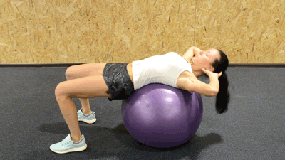 Сядьте на фит-бол, заложите руки за голову, затем отклонитесь назад. Контролированным движением за счет мышц живота приподнимите корпус, задержитесь на секунду и снова опуститесь вниз. Бедра при выполнении должны оставаться параллельными полу. 