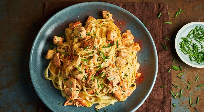 ИНГРЕДИЕНТЫ 400 г филе свежего лосося без кожи
300 г горбуши горячего копчения
400 г феттуччине
400 г сливок жирностью 20%
4 зубчика чеснока
10–12 перьев шнитт-лука
1 ст. л. сливочного масла
0,5 ч. л. сладкой паприки
соль, свежемолотый черный перец
ПОШАГОВЫЙ РЕЦЕПТ ПРИГОТОВЛЕНИЯ
Шаг 1
Нарежьте свежую рыбу кубиками со стороной 2 см, посолите, поперчите. Копченую рыбу разберите на кусочки, удаляя кожу и косточки.
Шаг 2
Поставьте вариться пасту в большом количестве соленого кипятка согласно инструкции на упаковке.
Шаг 3
Раздавите, очистите и измельчите чеснок. Мелко нарежьте шнитт-лук.
Шаг 4
В большой глубокой сковороде растопите масло, положите чеснок, обжаривайте на небольшом огне 1 мин. Добавьте паприку и копченую рыбу, перемешайте. Влейте сливки, доведите до кипения, готовьте 2–3 мин.
Шаг 5
Положите свежую рыбу, снова доведите до кипения, снимите с огня, всыпьте шнитт-лук, оставив немного для украшения. Посолите, если нужно.
Шаг 6
Подогрейте тарелки в микроволновке или духовке. Готовую пасту откиньте на дуршлаг, стряхните воду, переложите пасту в соус, перемешайте и сразу разложите по тарелкам. Еще поперчите и посыпьте оставшимся шнитт-луком. Подавайте немедленно.