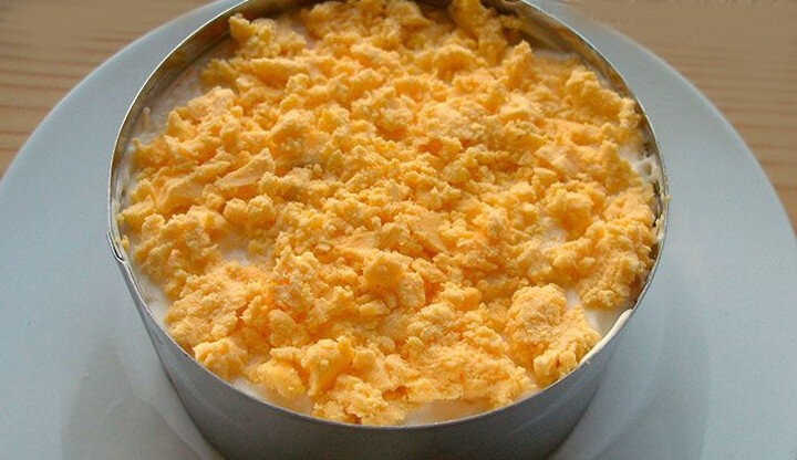 
8. Далее выкладываем половину натертых яиц. Слегка промазываем соусом.
9. Следующим слоем идет морковка, которую промазываем нашим чесночным соусом.
10. Теперь очередь за 1/2 сыра. Этот слой обильно поливаем соусом.
11. Повторяем слои в той же последовательности, используя оставшуюся часть ингредиентов. Не забываем каждый слой промазывать майонезным соусом.
12. Завершающий слой — мелко потертые желтки. Они же выступают как украшение салата «Нежность». Оставляем готовое блюдо пропитаться на несколько часов в холодильнике.