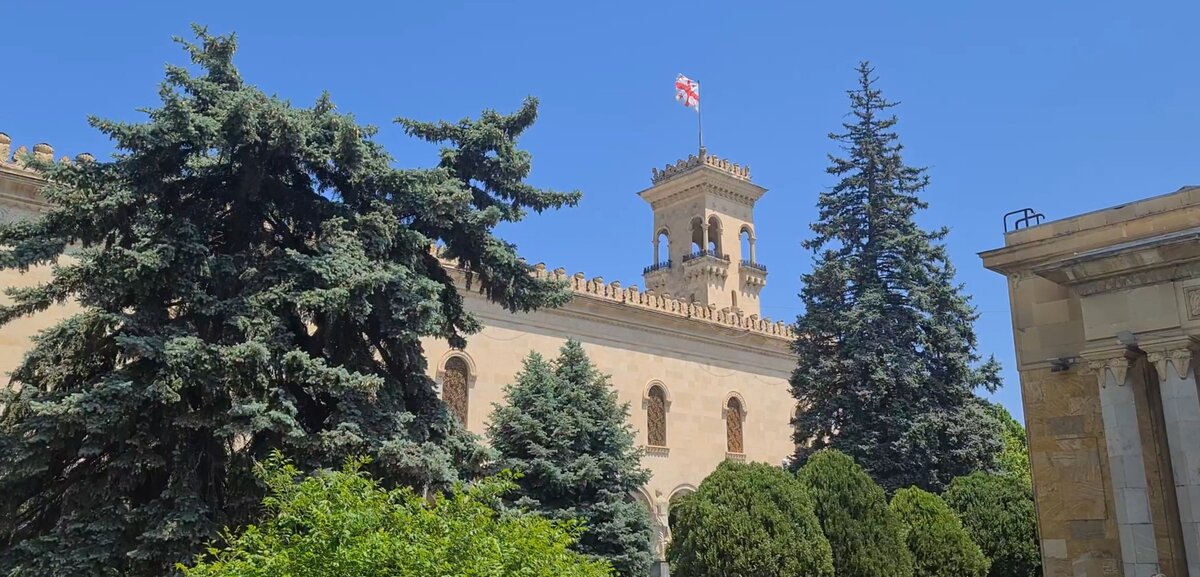 Грузинский флаг гордо развевается на фоне голубого неба