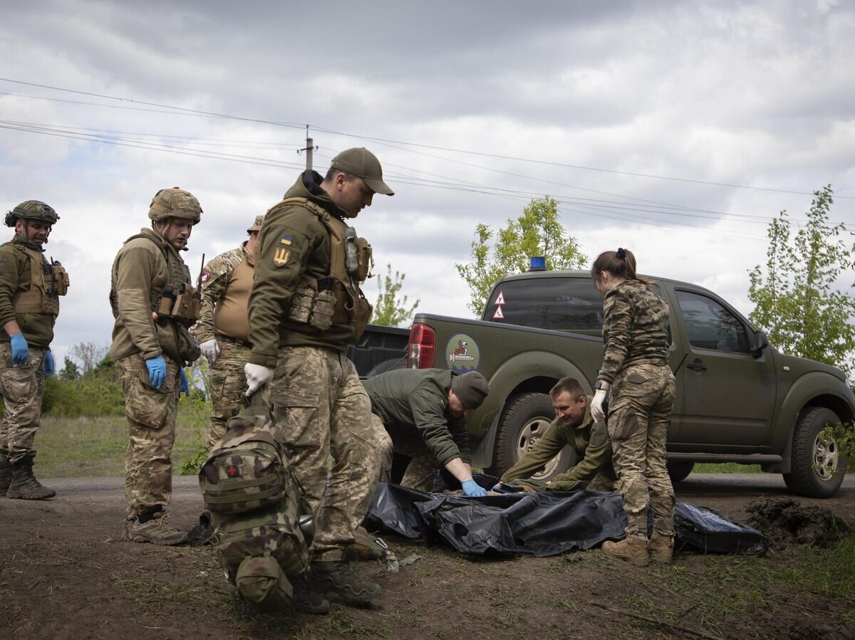    Военные медики укладывают тела убитых украинских солдат в пластиковые пакеты© AP Photo / Boghdan Kutiepov