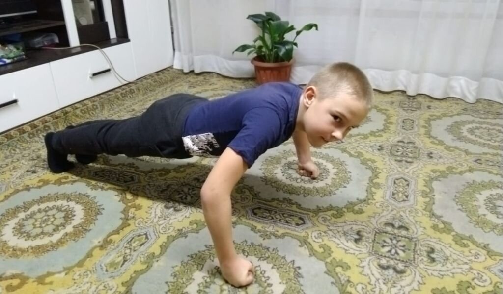 Сын выполняет спортивные упражнения