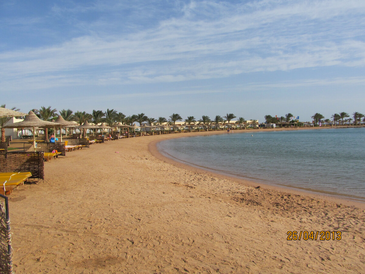 Песчаный пляж вокруг морской лагуны. Пальмы, зонтики, "заборчики" от ветра. Что интересно - в Хургаде такие ограждения есть практически во всех отелях, а вот в Шарме их незаметно.
