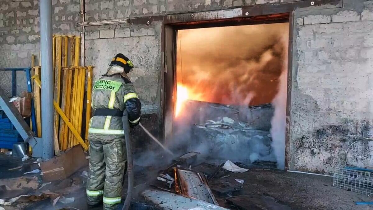    Сотрудник МЧС РФ тушит пожар в цехе по производству пластиковой тары в двухэтажном здании на улице Самарской в Волгограде. Стоп-кадр видео© РИА Новости / Пресс-служба МЧС РФ