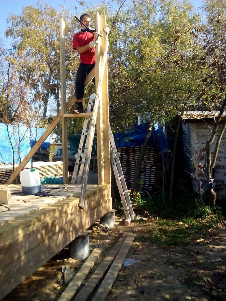 Чтобы было удобно ставить стены, мы настелили временный пол из доски 100×40 (для внутренних стен). Правда, он до сих пор там на месте, так что временным он будет до следующего лета.

Долго ходив вокруг да около, я резко беру две стойки, и не успев испугаться, сколачиваю их и уже выставляю. Сдвоенные стойки двух смежных стен выставляются по уровню и скрепляются в двух направлениях укосами к лагам снаружи дома.
