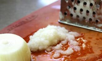 Лук натираем на самой мелкой тёрке или пропускаем через мясорубку.