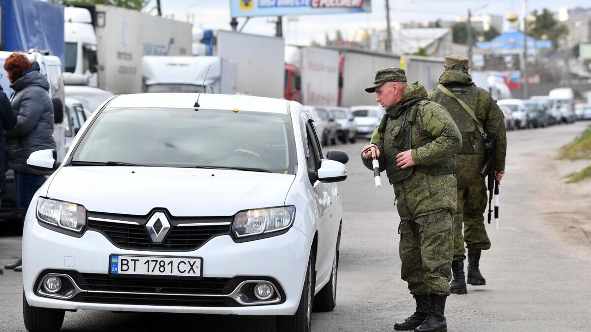    Сотрудники военной полиции регулируют движение в очереди на переправу в Херсоне© РИА Новости / Евгений Биятов