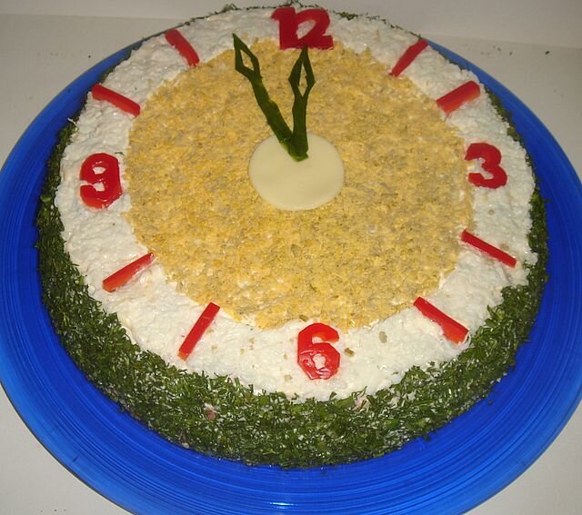 Салат в форме новогодних часов очень аппетитно и привлекательно смотрится на столе, подчеркивая праздничное настроение.