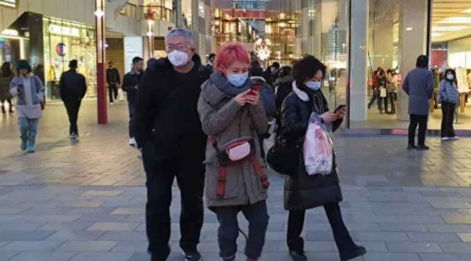 Прохожие в защитных масках на одной из улиц в Пекине