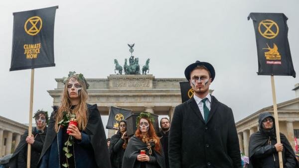 XR активисты на похоронном марше у Бранденбургских ворот в Берлине 8 октября 2019 года. МИШЕЛЬ ТАНТУССИ / AFP