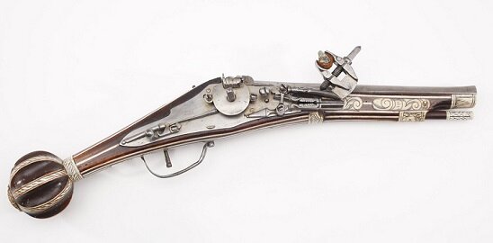 Пистолет с кремневым колесцовым замком, германские земли, вторая половина 16 века. В тисочках закреплялся кремень или пирит. Затем эти тиски вручную (было и не вручную - по нажатию спускового крючка) подводились к полочке, на которую отсыпалась часть пороха от заряда и которая сообщалась каналом со стволом. Под полочкой находилось вращающееся колесцо, которое заводилось специальным ключом. При нажатии на спусковой крючок, колесцо быстро вращалось, высекало из кремня искры, искры воспламеняли порох, производился выстрел.