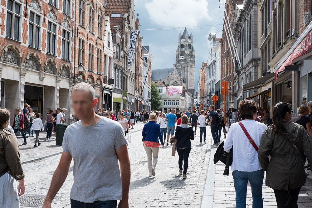 Лица узнаваемых людей размыты. Логотипы и уличные знаки залиты сплошным цветом или размыты.