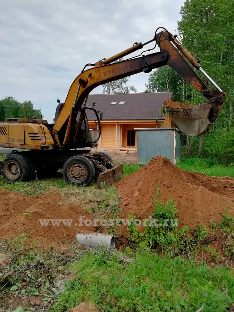 Экскаватор ЕК-14 закапывает песком дренажные трубы переезда на участок.