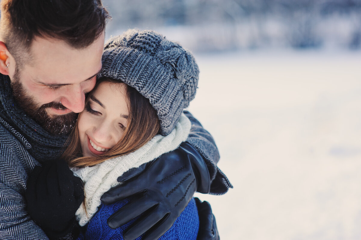 Совместный внешне. Embracing couple wearing woolen hats.