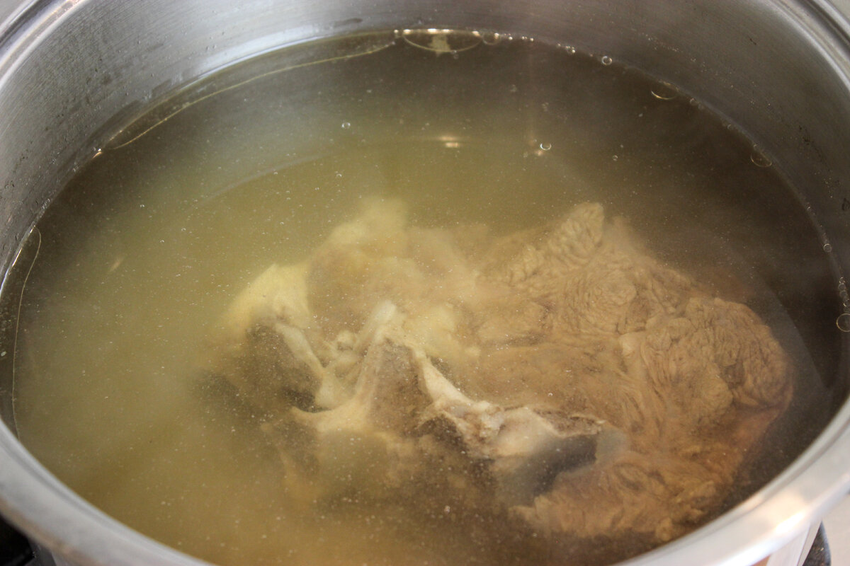 Приготовить бульон. Налить в кастрюлю воды, примерно 3 литра, положить мясо, довести до кипения. Когда появится пенка (нам не нужен ее вкус) полностью слить воду. Затем налить чистой холодной воды, положить мясо в кастрюлю, довести до кипения. Убавить огонь, варить на медленном огне, чтобы едва булькало. Прикрыть крышкой, варить 2-2,5 часа до мягкости мяса. Тогда бульон будет прозрачный и наваристый. 