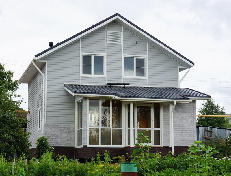 Дом с отделкой сайдингом Docke елочка цвет Халва и фасадными панелями docke Stein молочный