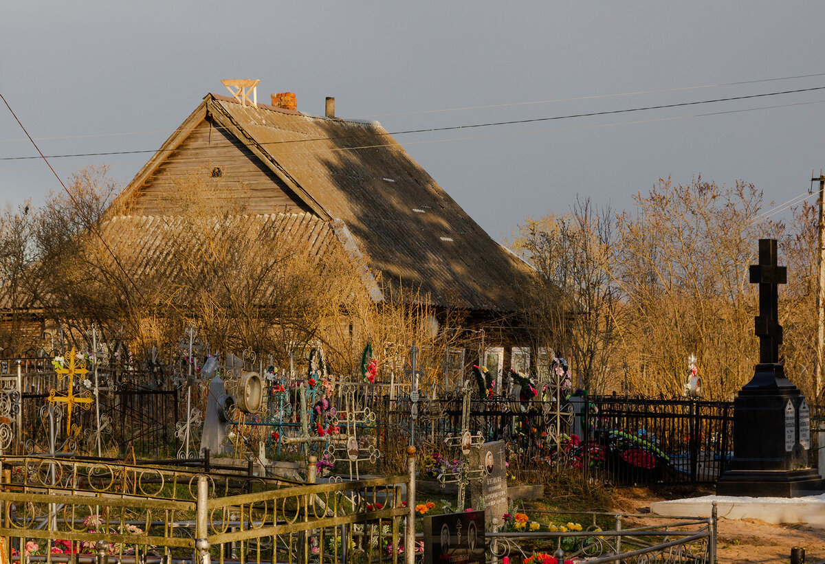 Памятник, на фоне старого деревенского дома. Атмосферно