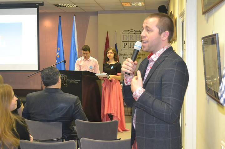 9.02.2014. Рамазан Алпаут, создатель московской кумыкской организации (после ребрендинга носит название МКО "Qumuqlar") выступает на Вечере кумыкской культуры. Именно здесь общественность впервые познакомилась с новой символикой. Два флага (на фото они видны на заднем плане) торжественно внесли в зал дети в национальных кумыкских костюмах.