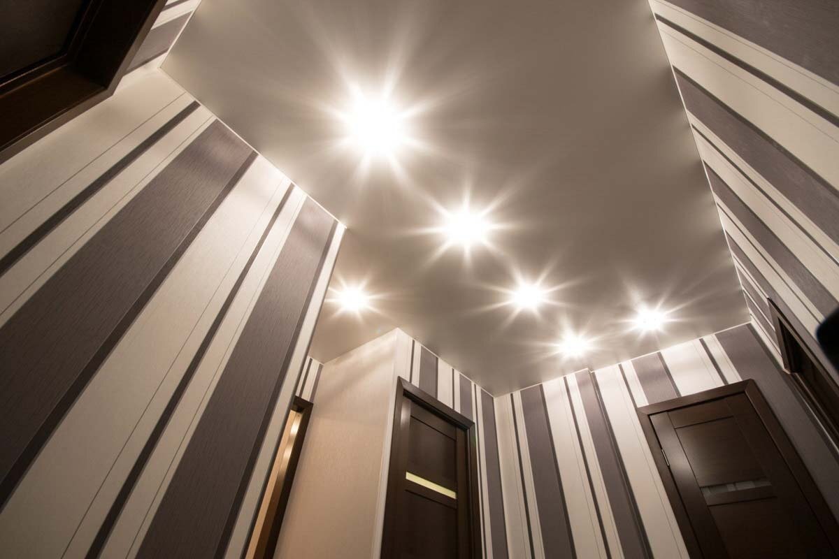 1.Пленка, из которой изготовлено полотно, очень пластична и позволяет декорировать и простые, и сложные по конфигурации объекты. Часто ее используют для отделки многоуровневых потолков, арок, сводов и шатров. В результате получается эффект идеально ровного и твердого потолка.
2. Монтаж установки занимает не более 3-х часов. При этом не остается пыли и грязи, как при альтернативных вариантах отделки. А после демонтажа полотно можно использовать вторично. Это удобно, если намечается переезд, и необходимо забрать с собой «многоразовую отделку»
3. Пленка обладает антистатическими свойствами, поэтому к ее поверхности не притягиваются пыль и грязь. Производители уверяют, что ухаживать за такой отделкой практически не нужно, но если есть желание, полотно в любой момент можно помыть простой водой. Кроме того, на описываемом материале никогда не образуется конденсат, поэтому пленку ПВХ можно использовать для декорирования ванных комнат и крытых бассейнов.
4. Конструкция натяжного потолка такова, что позволяет в образовавшейся между пленкой и потолочной плитой нише разместить инженерные коммуникации — вентиляционную разводку, электрические провода, акустические системы. Можно устанавливать и точечное освещение. Только мощность ламп в данном случае ограничена. А простота монтажа и демонтажа обеспечивает легкий доступ к подобной технической начинке.
5. Полотно обладает водонепроницаемыми свойствами, поэтому способно уберечь дорогостоящий интерьер от потопа соседей. Специалисты отмечают, что данная установка дополнительно обеспечивает тепло- и звукоизоляцию, что очень актуально для многоквартирных домов.
6. Монтаж конструкции «крадет» у высоты помещения минимальное количество сантиметров — всего 3.