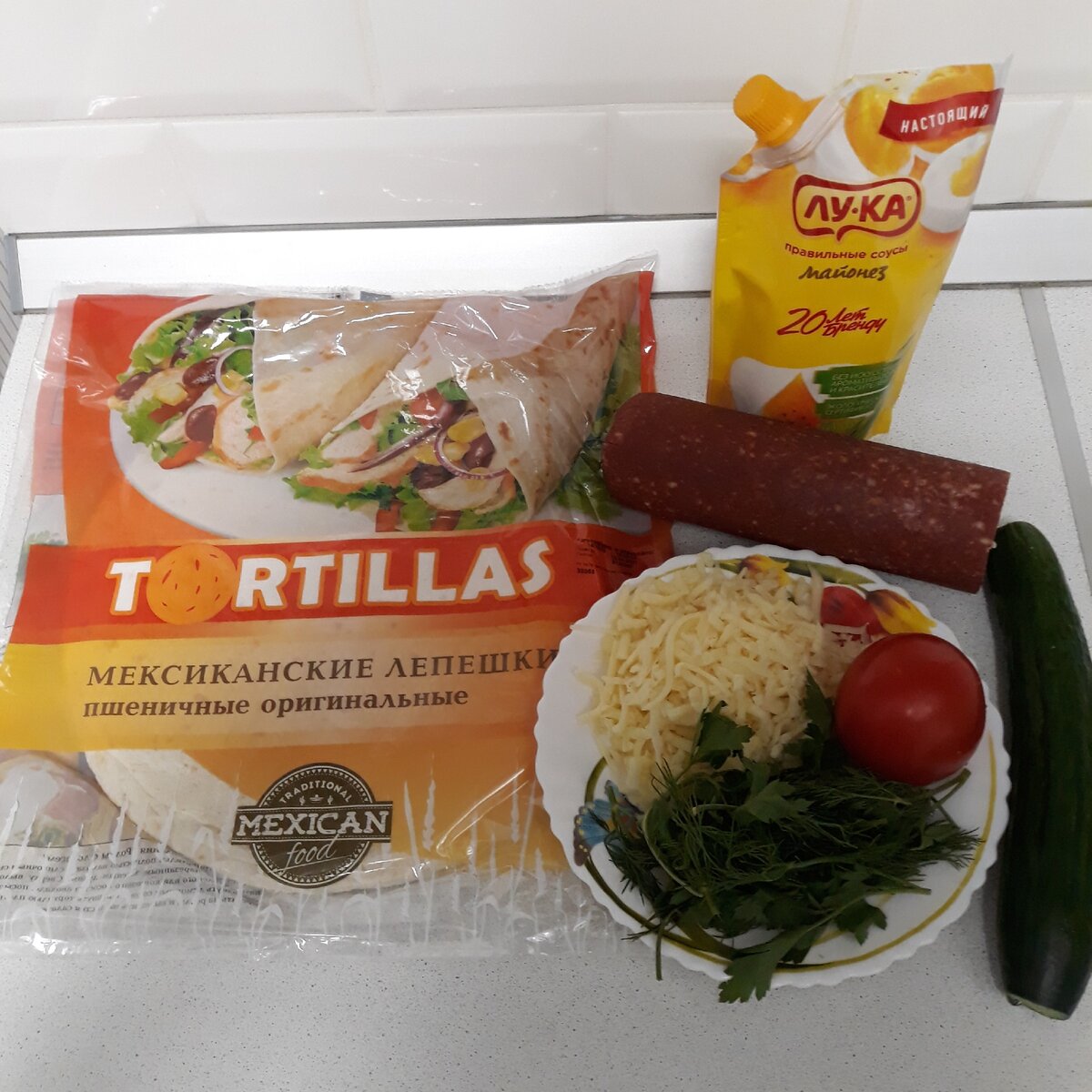 Ингредиенты : лепёшки tortillas. огурец 1 шт, помидор 1 шт, сыр 50 гр, колбаса копчёная 100 гр, зелень укропа и петрушки,майонез , зубчик чеснока.