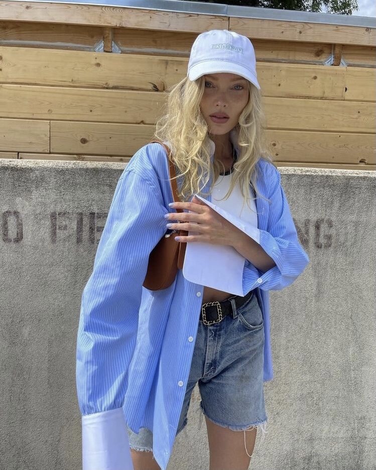 Джинсовые шорты средней длины в сочетании с белым топом и голубой оверсайз-рубашкой