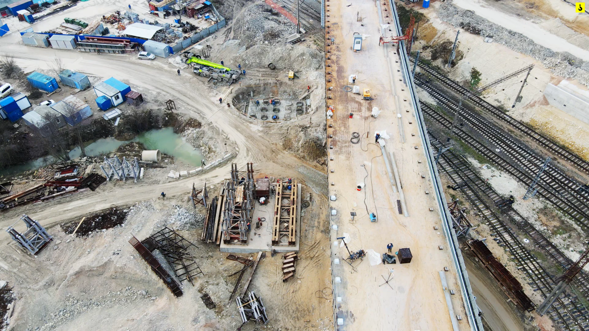 Идет сборка конструкций стапеля, видно свайное поле промежуточной опоры второй очереди путепровода.