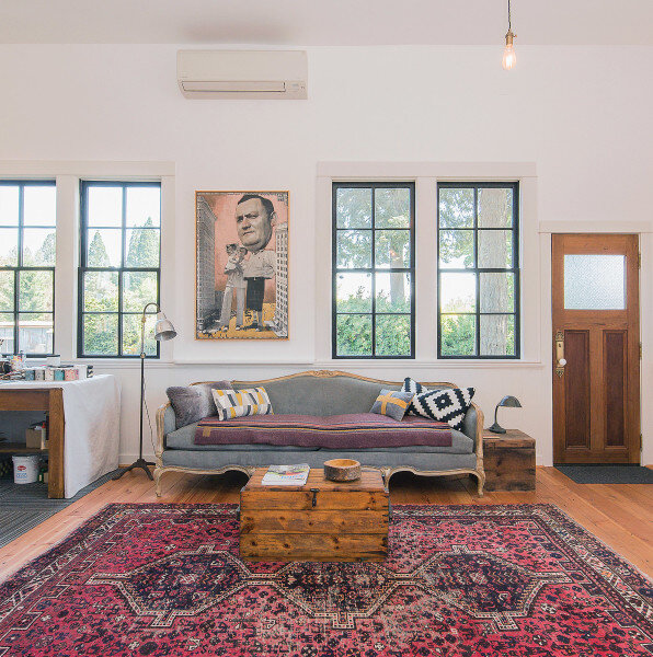 Гостиную часть комнаты украшает винтажный диван, который удалось восстановить, а также классический ковёр былых времён.