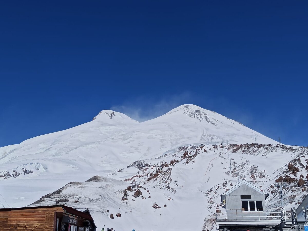 Вершины Эльбруса: западная (5644 м) и восточная (5633 м). Кажется, что до них рукой подать. Но это оптическая иллюзия: только по высоте разница составляет 2100 м (снимок сделан со станции Мир, высота 3500 м). 