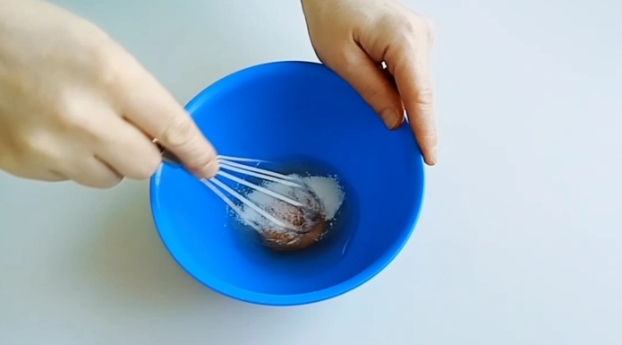 В чашу разбиваем одно яйцо, всыпаем две столовой ложки сахара и все тщательно перемешиваем