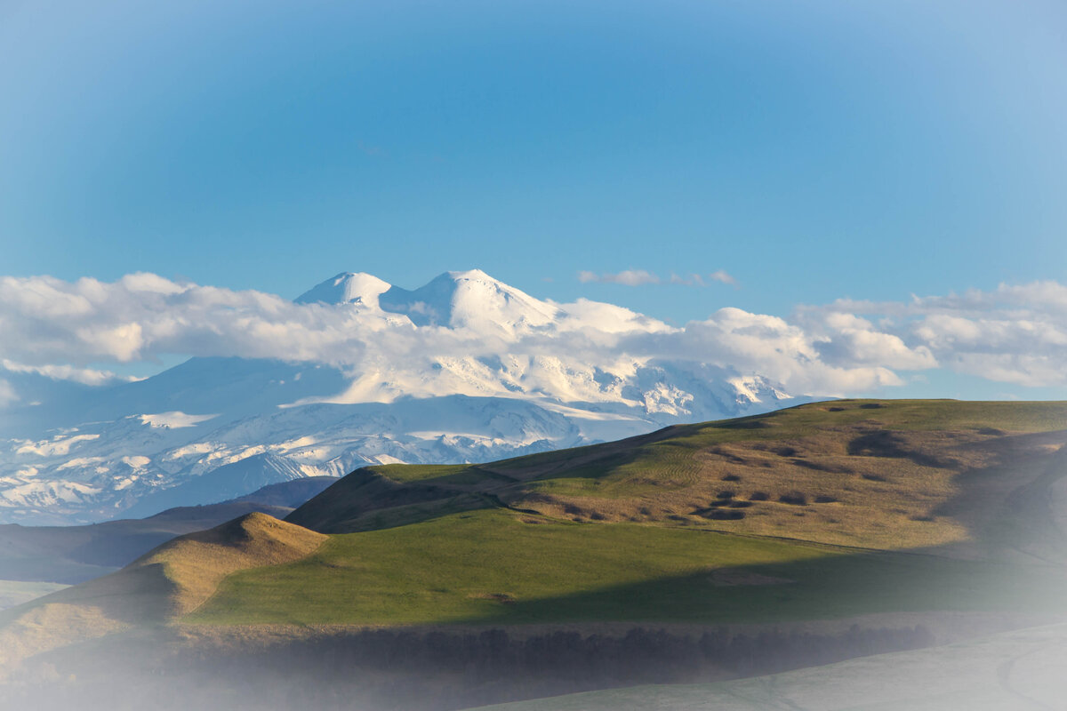 Это самая высокая гора России и Европы и входит в рейтинг семи высочайших вершин мира. Эльбрус имеет две вершины, западная достигает высоты 5642 м. Восточная чуть ниже — 5621 м.  Этот могучий великан величественно возвышается над вершинами Кавказского хребта и увидеть его во всей красе удается не каждому. Часто вершины закрыты облаками  а то и весь Эльбрус скрыт от глаз путешественников.  Давайте полюбуемся этой красотой.
