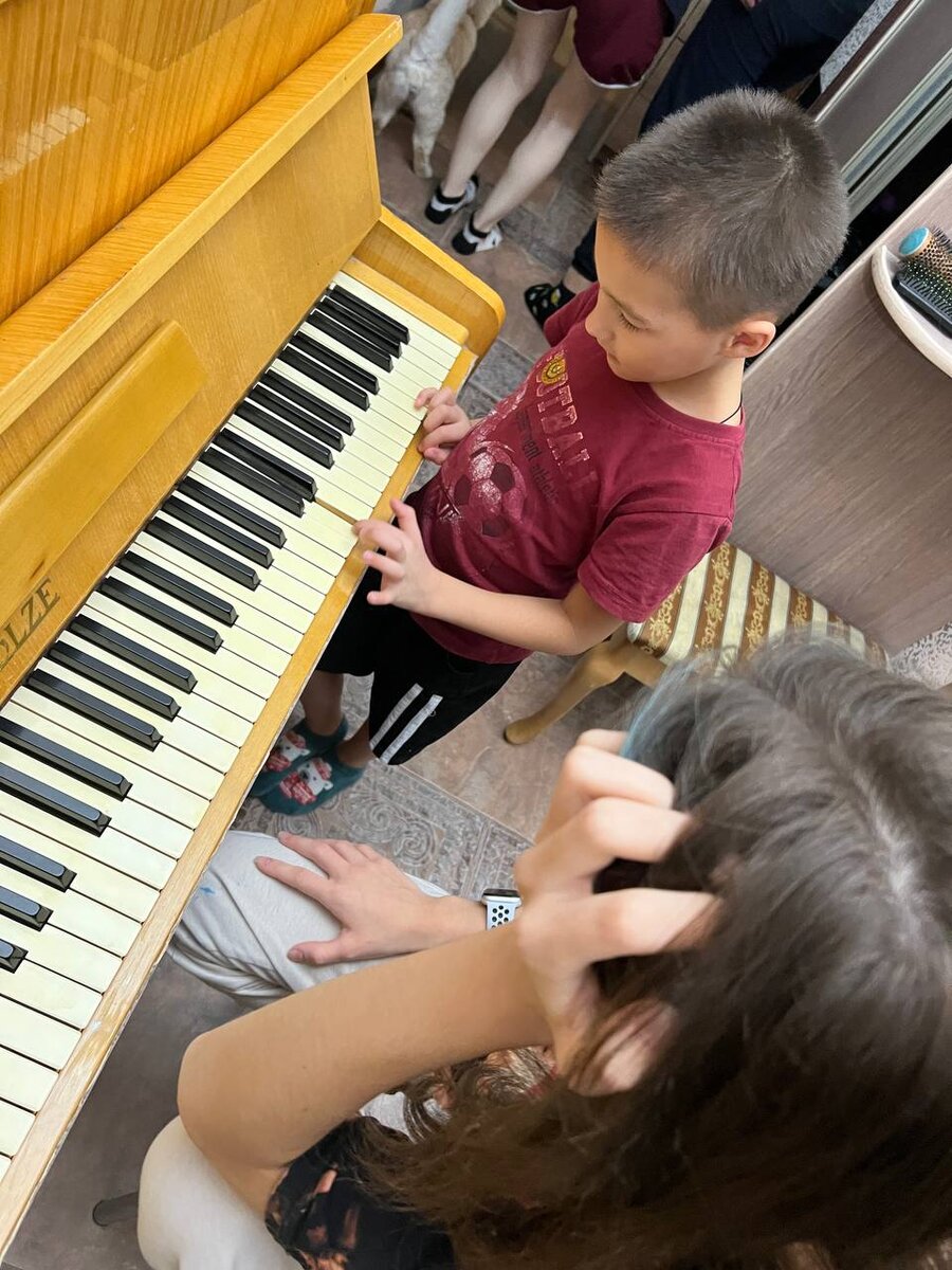 Настя учит Максима наигрывать простенькую мелодию, а на втором плане видны ноги Милы и кота Милана