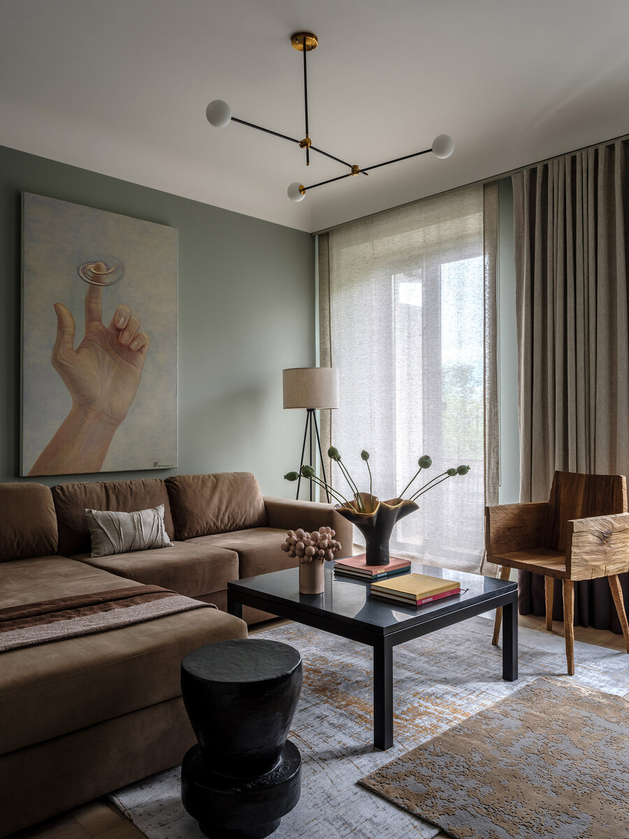 Гостиная. Диван, Eichholtz; журнальный столик, Crate and Barrel; бежевая ваза и черный столик, savour.design; торшер Woodland, Dutchbone; люстра Bullarum ST-3, Intueri Light; льняные шторы, Casamance; деревянное кресло, SÓHA; ковры, Jerome Botanic; картина Анастасии Копытцевой “Начало”.