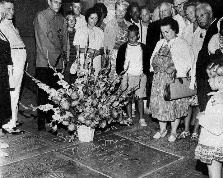 Поклонники кладут цветы на мостовую перед Китайским театром Граумана в Лос-Анджелесе рядом с мемориальной доской, на которой 26 июня 1953 года Мэрилин Монро оставила отпечатки своих ладоней.