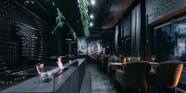 Живое пламя камина на экотопливе – беспроигрышный вариант декора для барной стойки. Чтобы танцующие языки не нарушали комфорта гостей, дизайнеры дополнили конструкцию защитными бортами из прозрачного огнеупорного стекла.