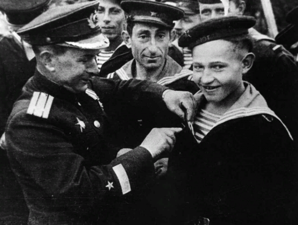 Командир бригады торпедных катеров А.В. Кузьмин вручает Саше Ковалеву орден Красной Звезды.