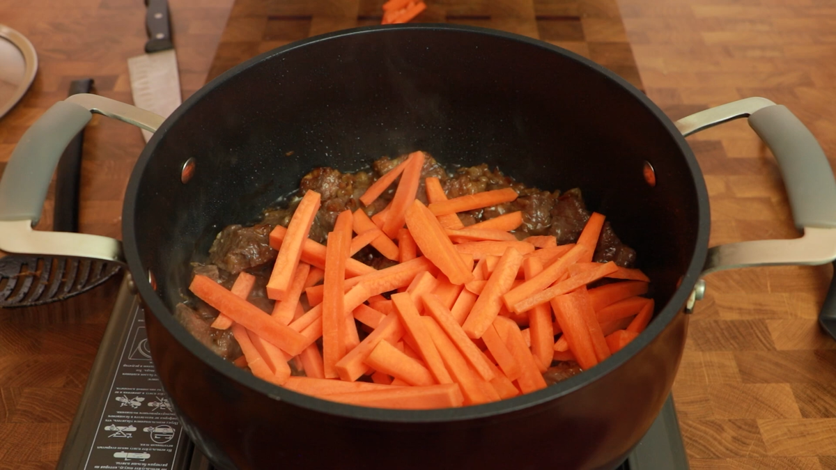 5. Морковь нарезаем брусочком (0,3-0,5 см в толщину и 4-5 см в длину) и закладываем после мяса. Обжариваем до небольшого размягчения самой моркови, примерно 10 минут на сильном огне, перемешивая, чтоб не горело ничего.